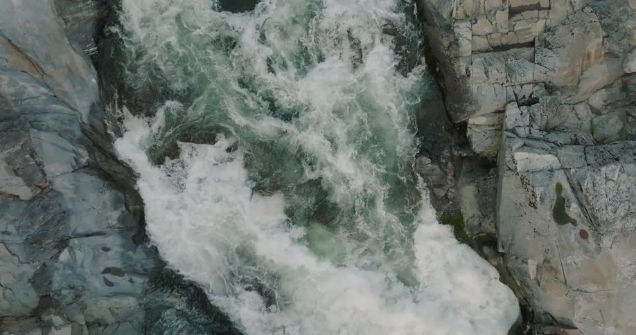 Aerial view of a river flowing between rocks and generating foam