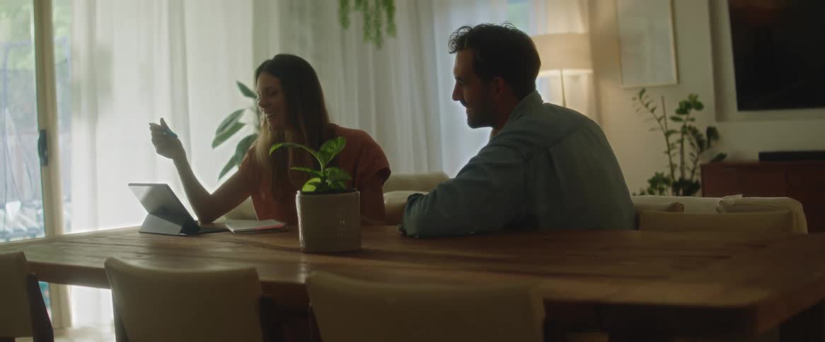 Two people talk while looking at a tablet
