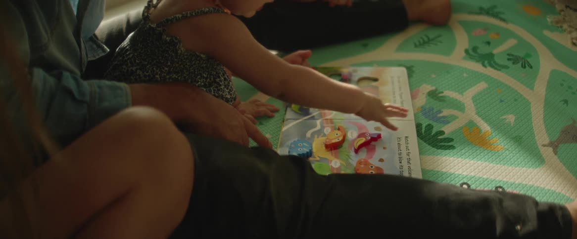 A parent is sitting with her baby as she plays a game