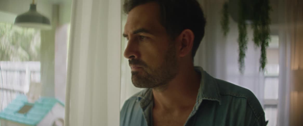A man in a living room looks worried then turns and walks away