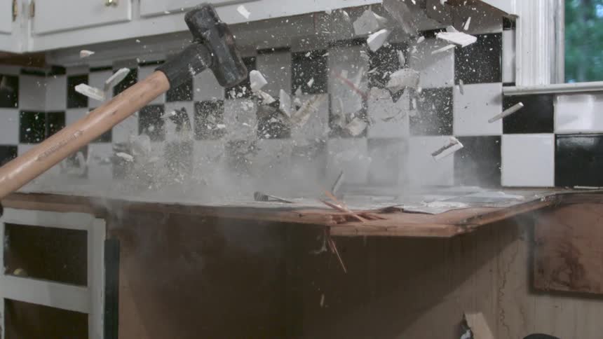 A sledgehammer crashes into a tile countertop