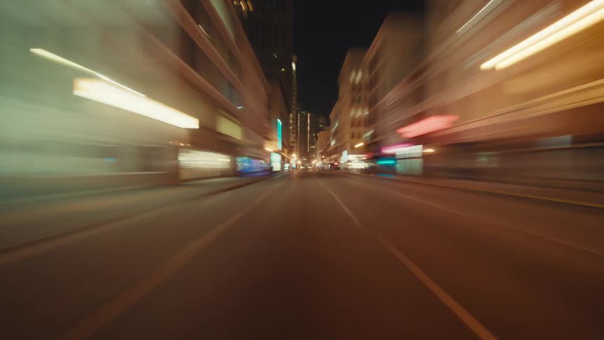 Traffic flows along brightly lit city streets at night