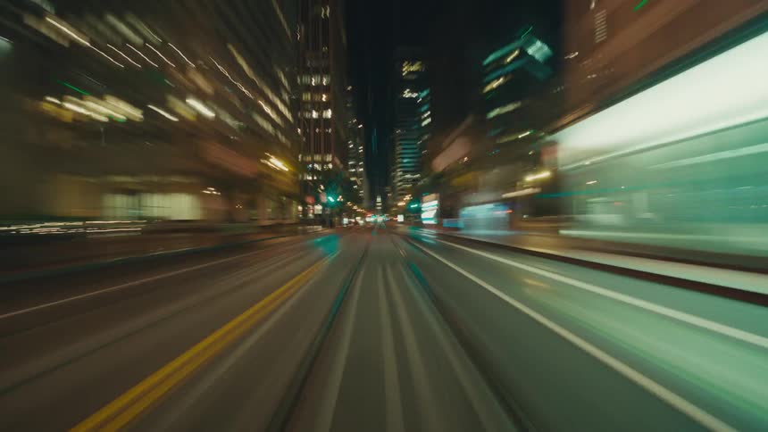 Downtown city buildings line a street illuminated by street lights at night