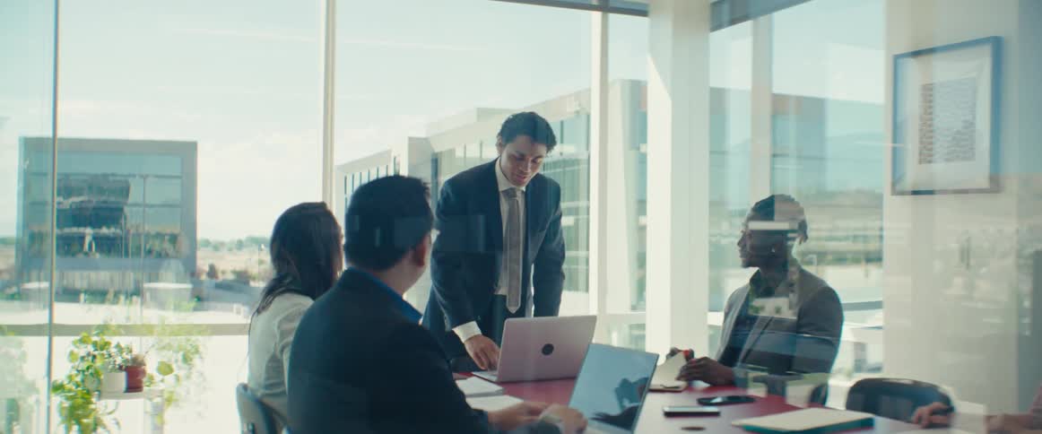 Man standing talking to other people sitting at an office desk