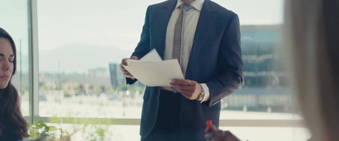 Standing businessman looks through documents during an office meeting