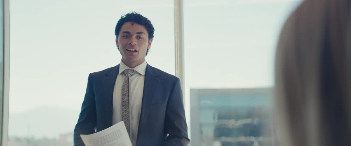 Man standing and talking to other people who are sitting in an office environment