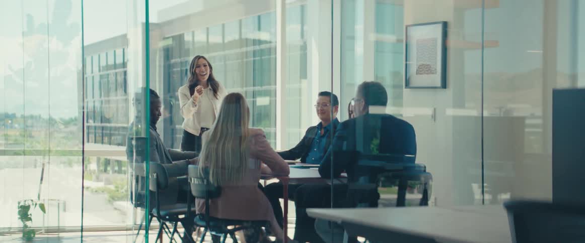 Colleagues gathered around a table in a modern office with large windows in a business meeting