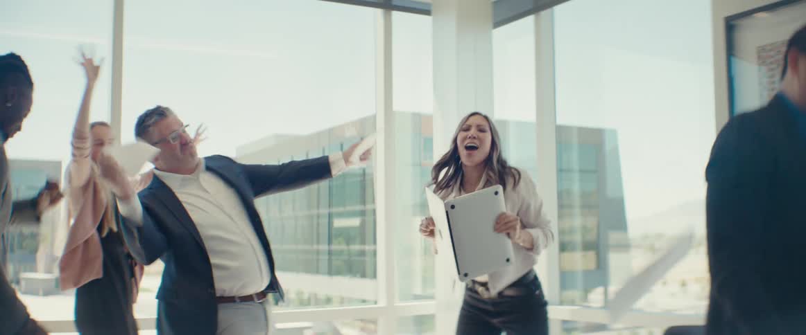 Men and women dancing and celebrating in an office room