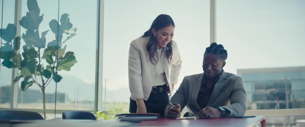 Man and woman with happy facial expressions talking to each other at a table in an office