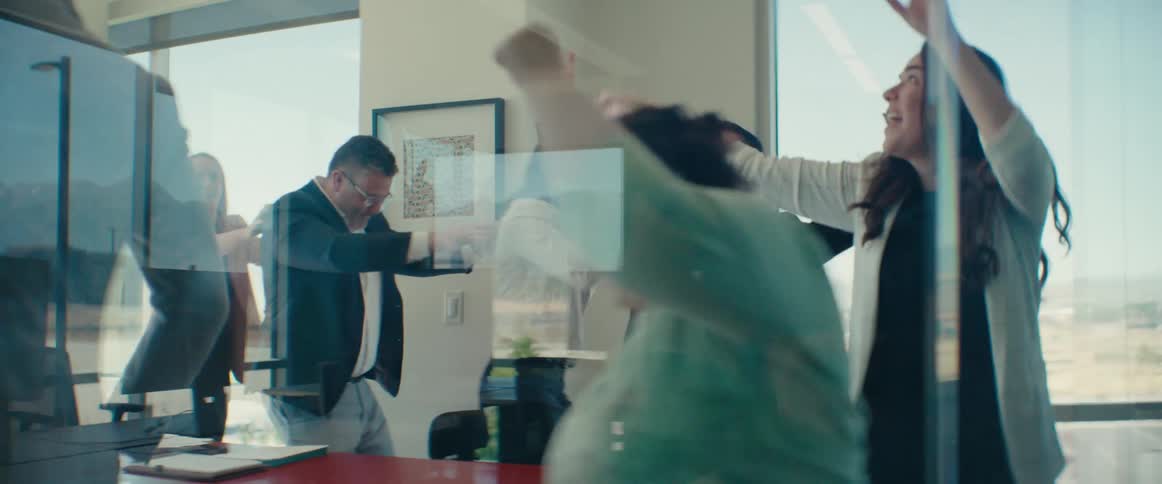 Group of friends in an office room walking one behind the other and dancing in a celebratory manner