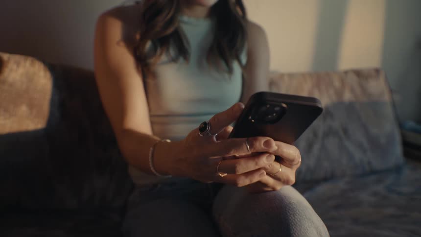 Woman sitting typing on a smartphone