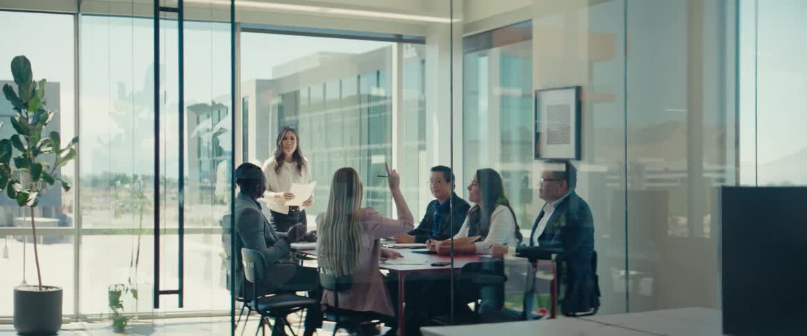A group of office workers conducts a meeting in a conference room