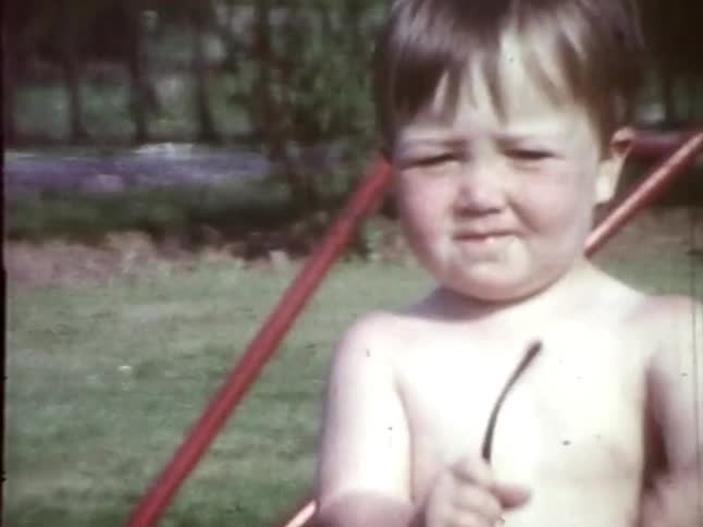 A toddler removes his sunglasses