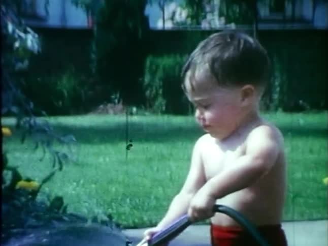 A little boy sprays water with a hose