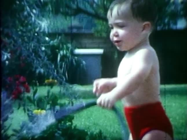 Happy little boy has fun with a hosepipe