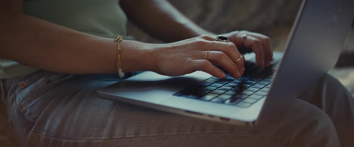 Close up of a womans hands typing on a laptop
