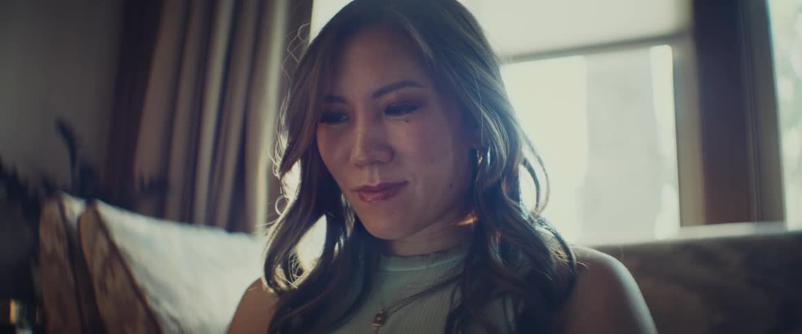 Close up of a young womans face as she sits in her living room smiling