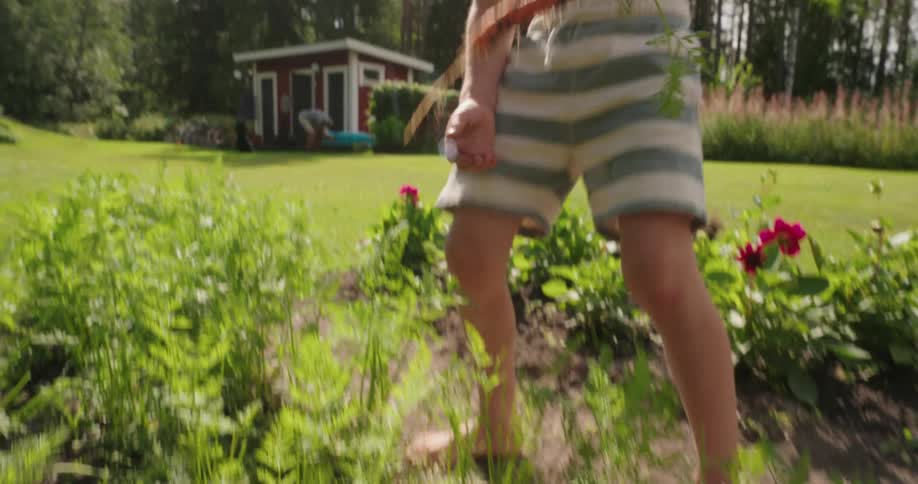 A boy pulling a carrot out of the garden and holding it up