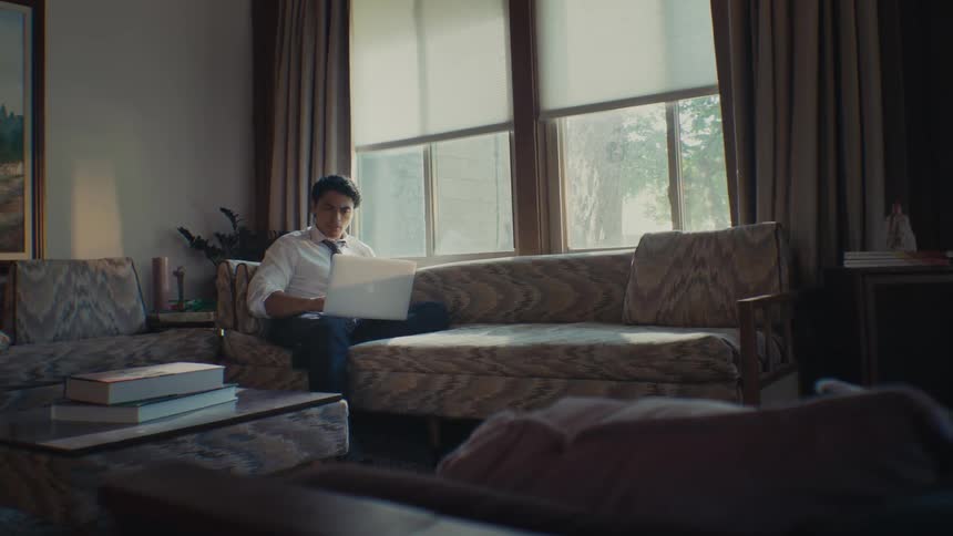 Man sitting in living room interacting with a laptop