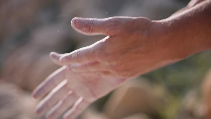 A closeup of a persons hands surrounded by dust particles as they clap their hands