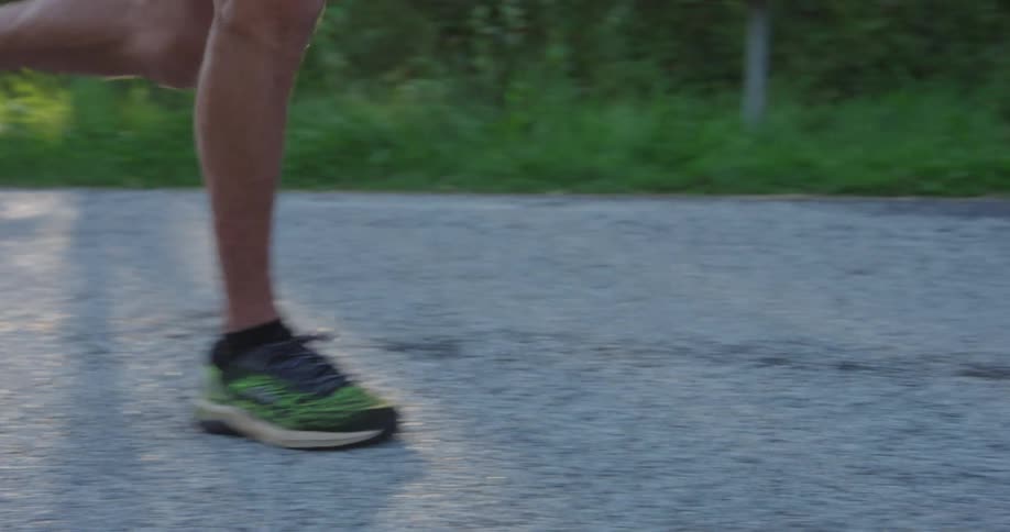Closeup of a man running on a road on a summer day