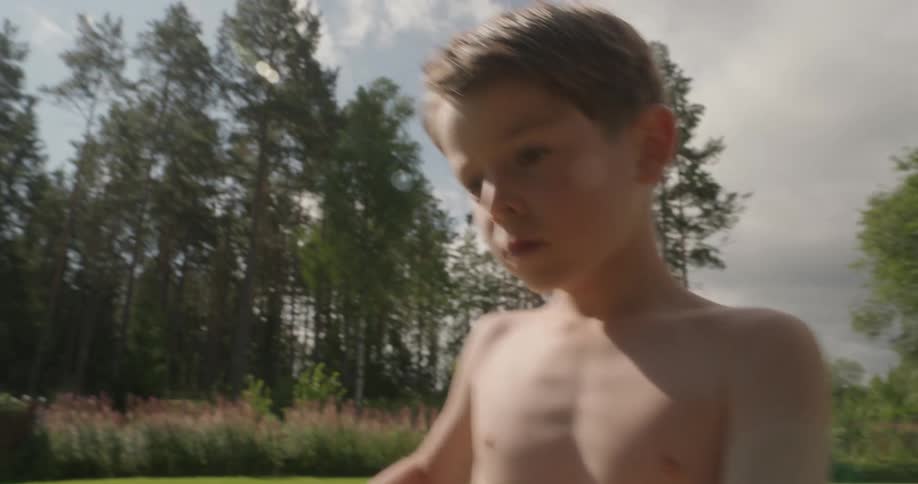 A young boy picks carrots from a garden and tosses them into a basket