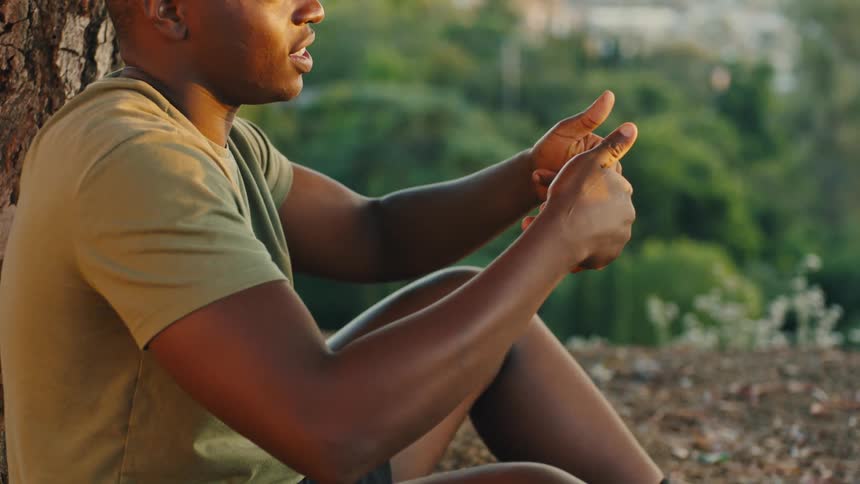 Man sitting around a tree talking in sign language