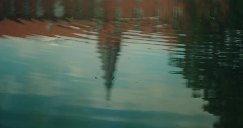 Reflection of a church spire in the water as ripples stream across the surface