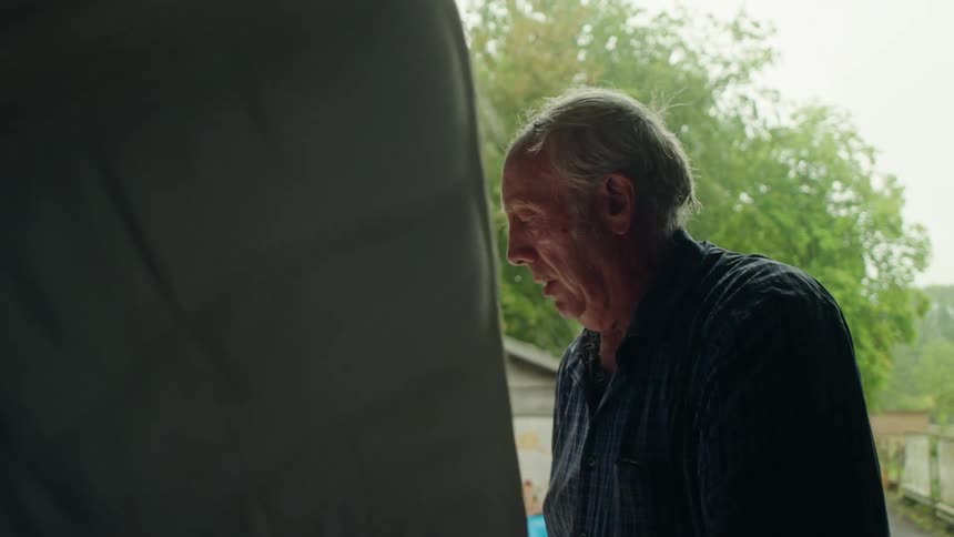 Elderly man loading a mattress into a truck