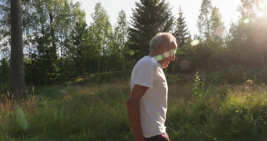 An elderly man walking through the countryside at morning