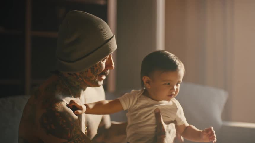 A man holding an infant child on his lap and holding her up in the air