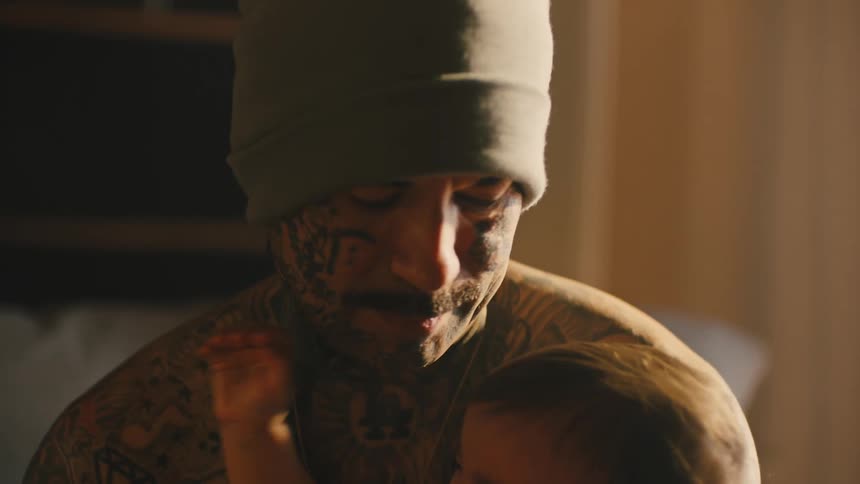 A father holding his infant daughter in his arms as she cries