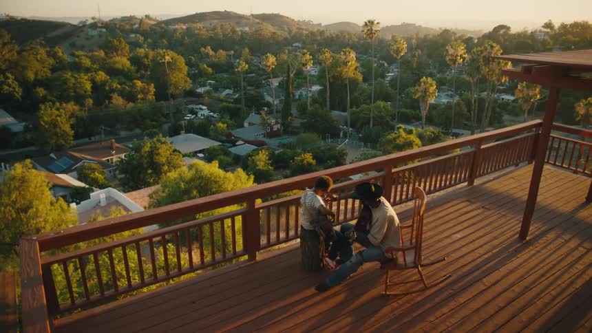 Man and a boy sitting on the balcony of a building playing guitar