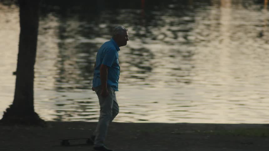 Man helping an elderly man skateboard