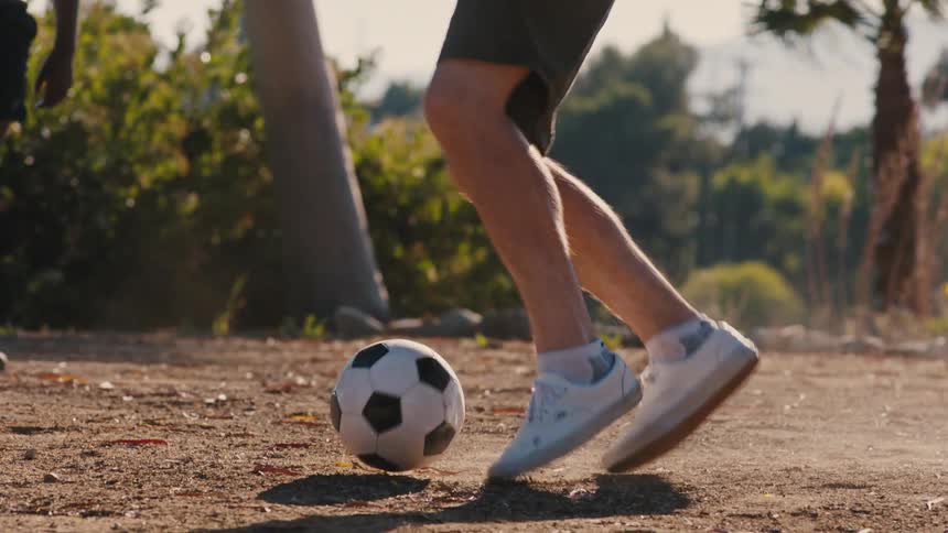 Two young men on a dirt field playing soccer