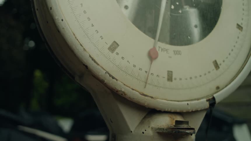 Close up of an old metal scale with the pointer moving
