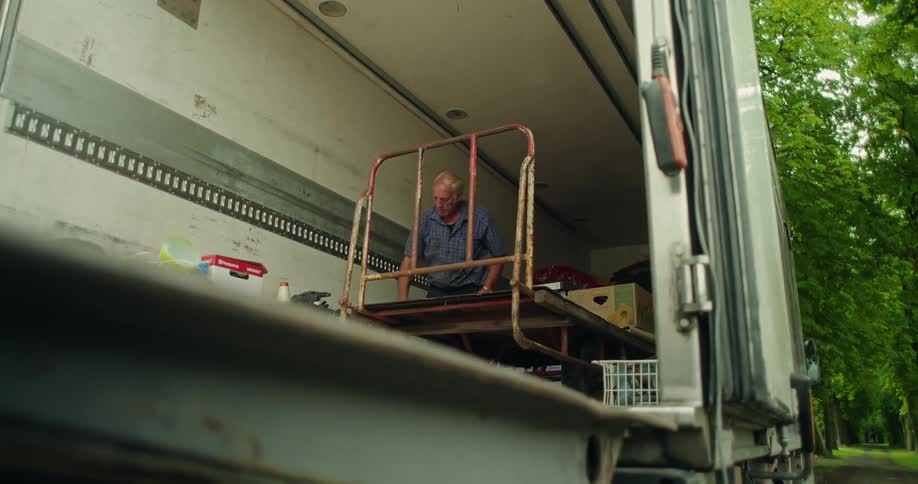 A man inside a cargo van loads up a cart