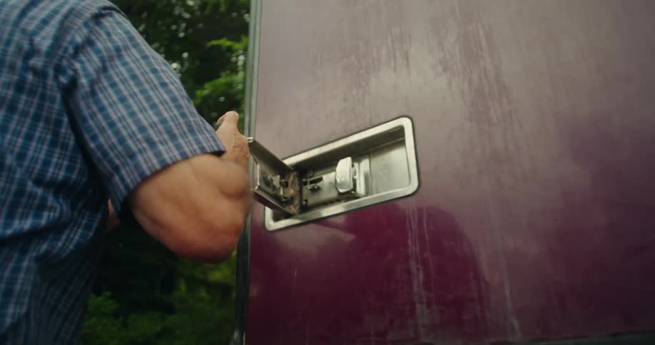 An older man closing a removal truck door and latching it closed