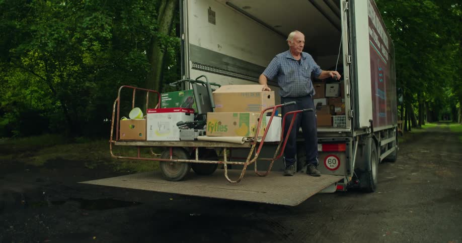 Elderly man getting off a truck with a load