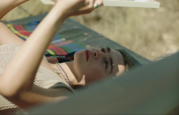 Young woman lying down looking at herself in a mirror that she holds with her hands