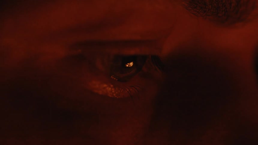 Closeup of an eye reflecting orange and red colors from a fire at night