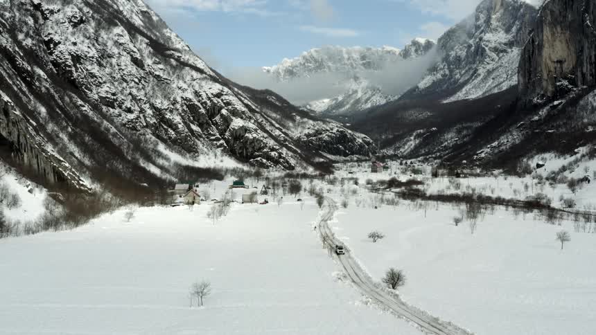 Aerial view of a car traveling in an environment surrounded by snowcapped mountains