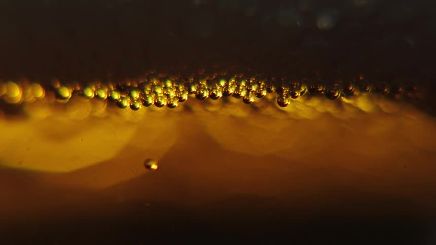 Golden beads float upwards in fluid and bump into other beads