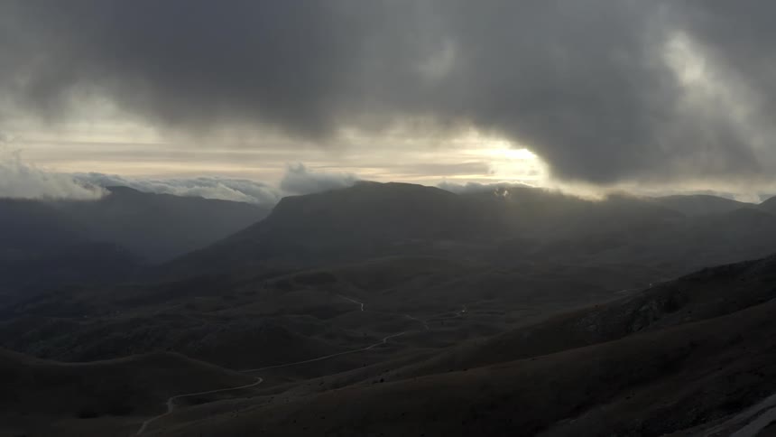 Highway winds through foggy mountainous terrain on a cloudy day
