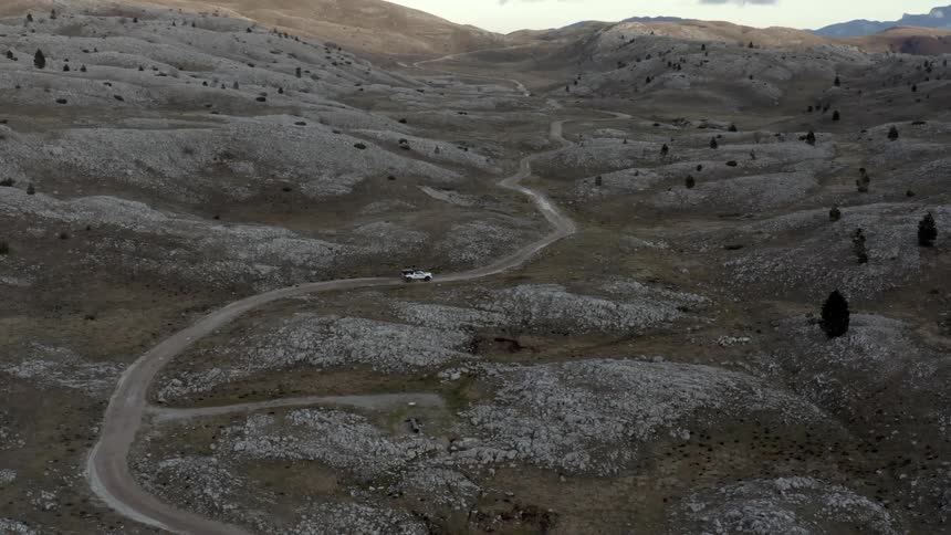 A vehicles drives on the winding dirt road