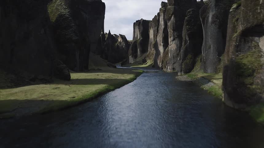 Aerial view of a stream winding between large rock formations on a cloudy day