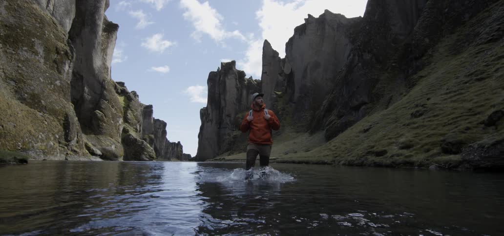 A hiker wades through a canyon river