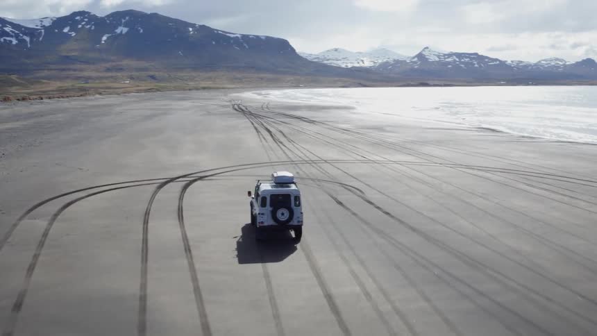 Suv rolling along a beach on a very overcast day