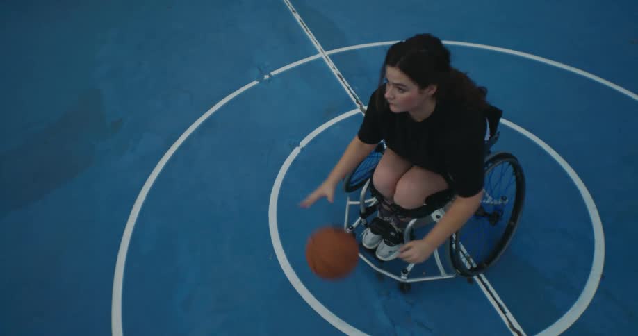 A young woman is playing wheelchair basketball