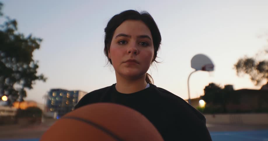 A teenage girl looking determined holding a basket ball